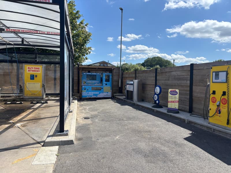 The outdoor self-service dog wash site in Abridge, with its covered wash bay, payment machines and fenced forecourt